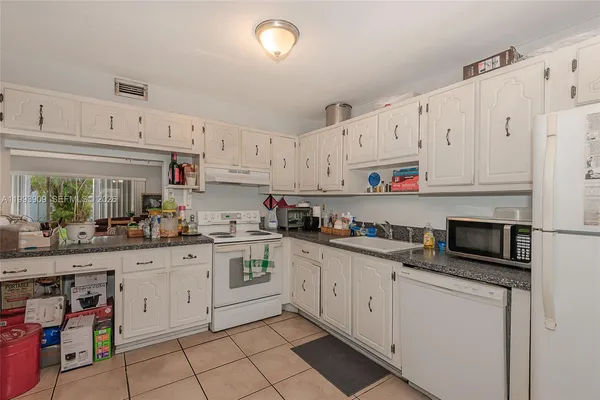 a kitchen with white cabinets and white appliances