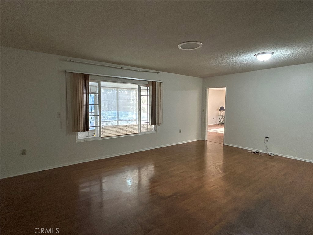 25915 Warwick Road Menifee, CA 92586 - Photo 10 of 34 an empty room with wooden floor and windows with curtains