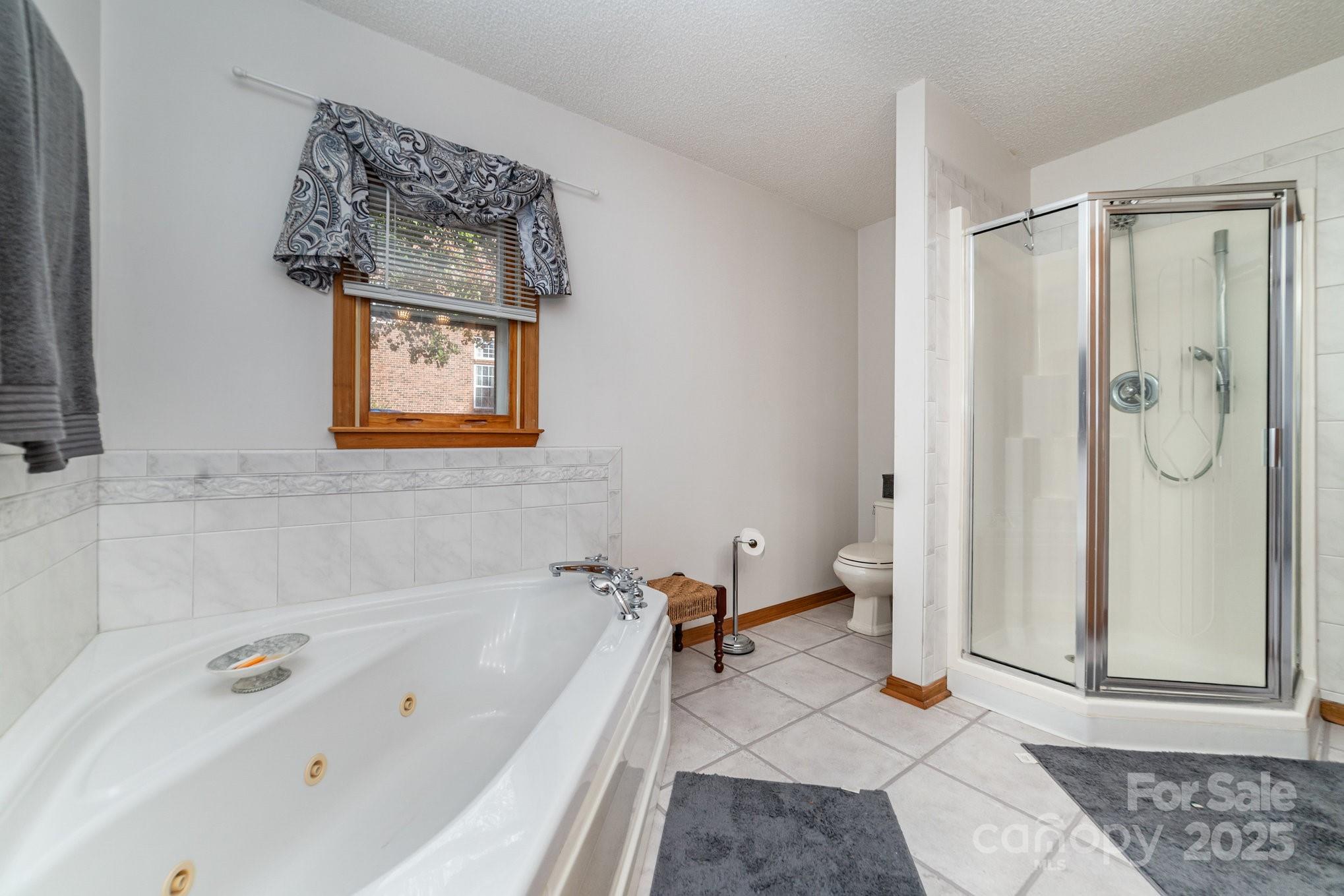 2595 Shamrock Road Harrisburg, NC 28075 - Photo 15 of 27 a bathroom with a tub a rug and a shower