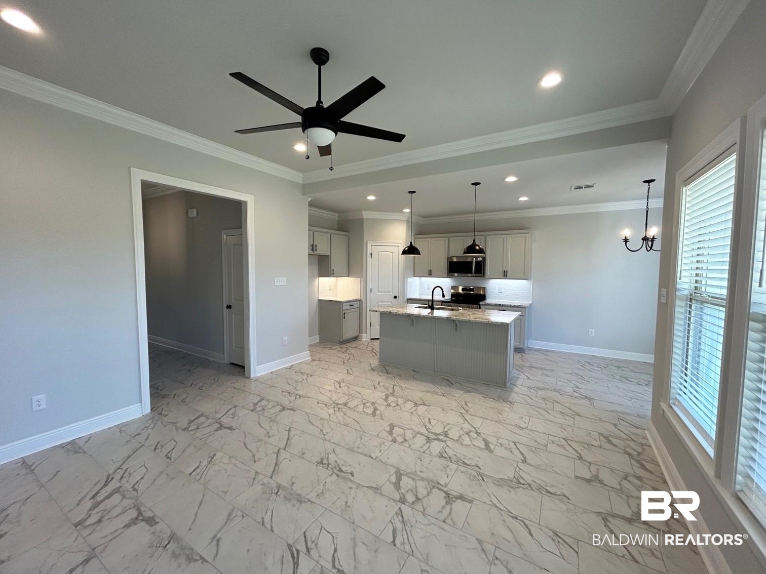 880 Sumter Loop Foley, AL 36535 - Photo 4 of 14 Kitchen with a center island with sink, appliances with stainless steel finishes, light stone countertops, crown molding, and decorative light fixtures