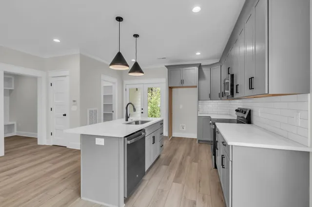 a kitchen with a stove a sink a refrigerator and white cabinets with wooden floor