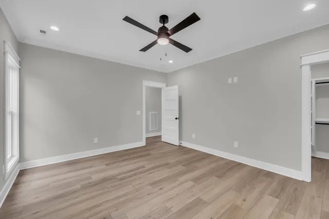 an empty room with wooden floor and ceiling fan