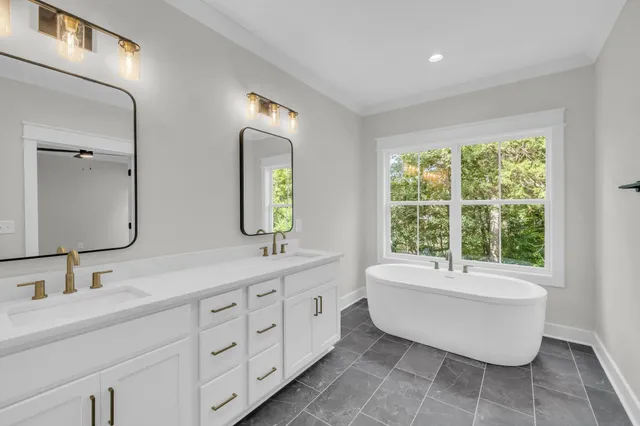 a spacious bathroom with double vanity sink a two mirror a window a bathtub and vanity