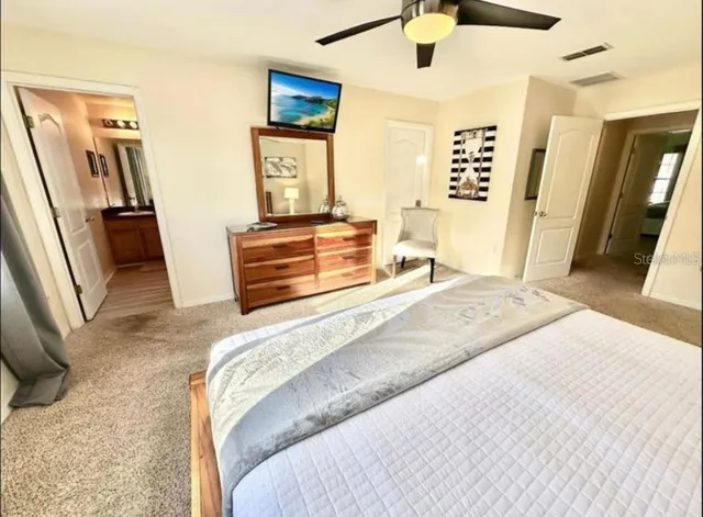 a bedroom with a bed and a flat tv screen on dresser