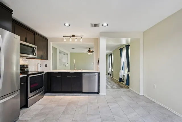 a large kitchen with stainless steel appliances granite countertop a refrigerator and a sink