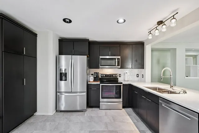 a large kitchen with stainless steel appliances granite countertop a refrigerator a sink a stove a microwave and wooden cabinets