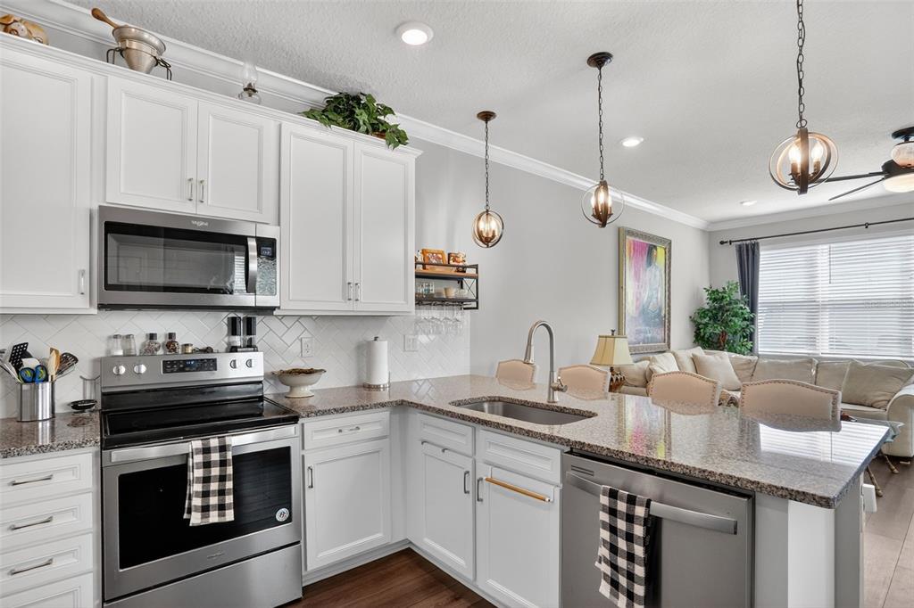 2222 Gopher Tortoise Terrace Oakland, FL 34787 - Photo 12 of 51 a kitchen with stainless steel appliances granite countertop a sink a stove and a wooden floors