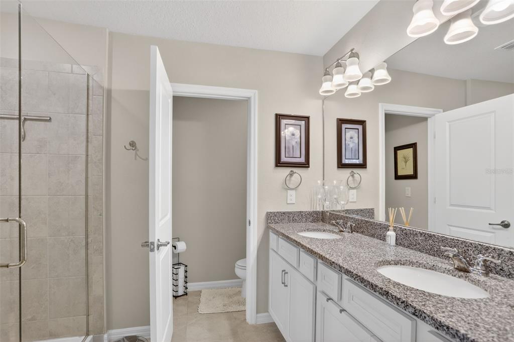 2222 Gopher Tortoise Terrace Oakland, FL 34787 - Photo 26 of 51 a bathroom with a granite countertop sink a mirror and a shower