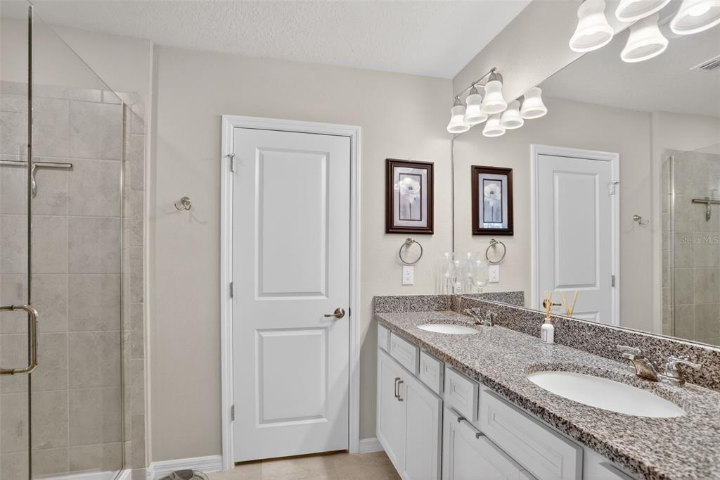 2222 Gopher Tortoise Terrace Oakland, FL 34787 - Photo 27 of 51 a bathroom with a granite countertop sink a mirror and a shower