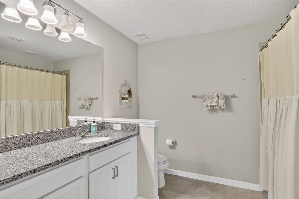 2222 Gopher Tortoise Terrace Oakland, FL 34787 - Photo 37 of 51 a bathroom with a granite countertop sink a mirror and a shower