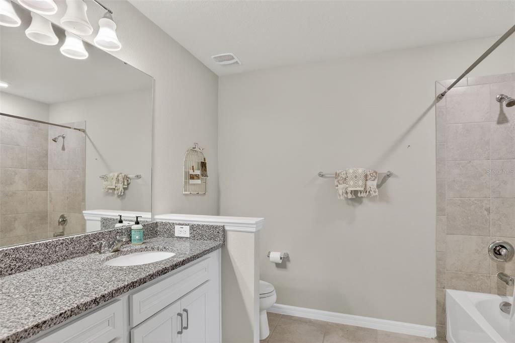 2222 Gopher Tortoise Terrace Oakland, FL 34787 - Photo 38 of 51 a bathroom with a granite countertop sink a mirror and a bathtub