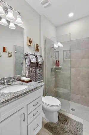 a bathroom with a granite countertop sink a toilet and shower