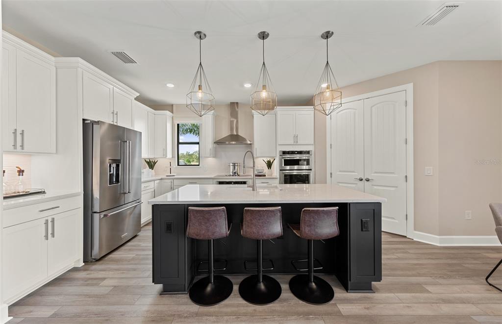 16427 Sapphire Point Drive Lakewood Ranch, FL 34211 - Photo 5 of 30 a kitchen with stainless steel appliances a dining table chairs refrigerator and microwave