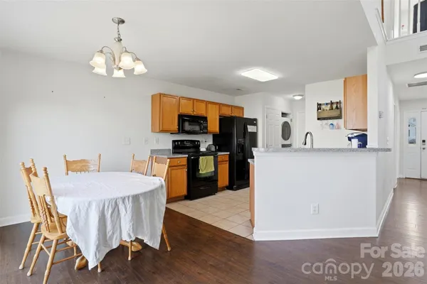 a kitchen with stainless steel appliances granite countertop a stove top oven a sink a dining table and chairs with wooden floor