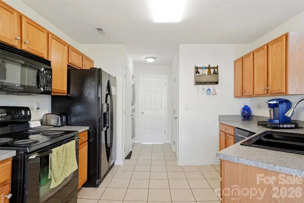 a kitchen with stainless steel appliances a stove a sink a refrigerator cabinets and a window