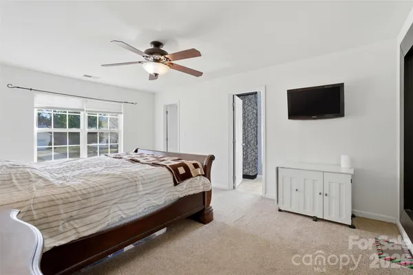 a bedroom with a bed a window and a flat screen tv
