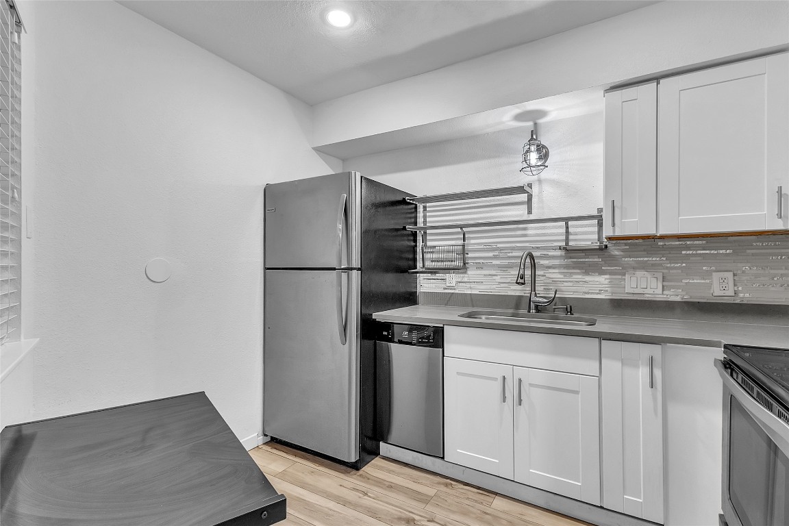 1840 Burton Drive, Unit 184 Austin, TX 78741 - Photo 12 of 23 Kitchen with white cabinetry, light wood-style floors, appliances with stainless steel finishes, backsplash, and recessed lighting