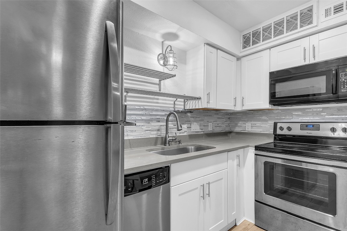 1840 Burton Drive, Unit 184 Austin, TX 78741 - Photo 4 of 23 Kitchen featuring stainless steel appliances, white cabinetry, backsplash, and light wood-style flooring
