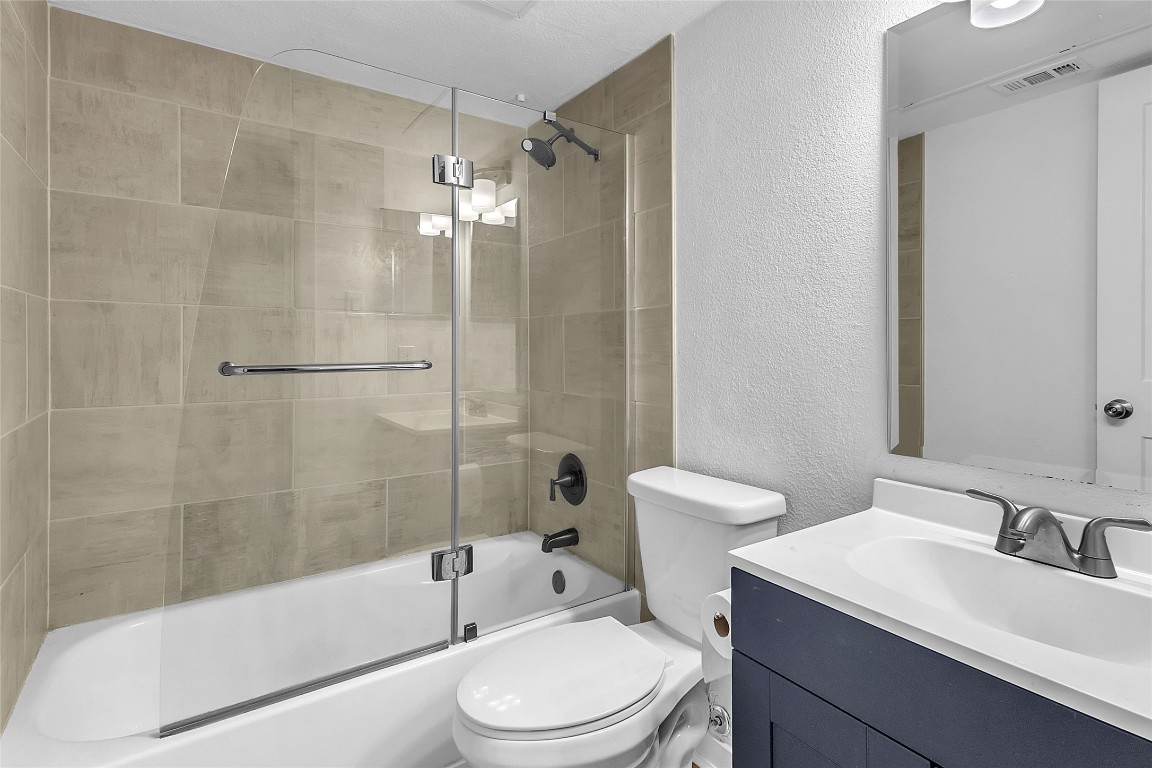 1840 Burton Drive, Unit 184 Austin, TX 78741 - Photo 6 of 23 Bathroom with a textured wall, combined bath / shower with glass door, and vanity