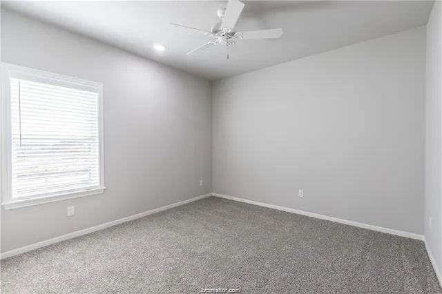 an empty room with a window and a fan