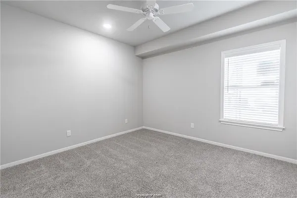 an empty room with a ceiling fan and window