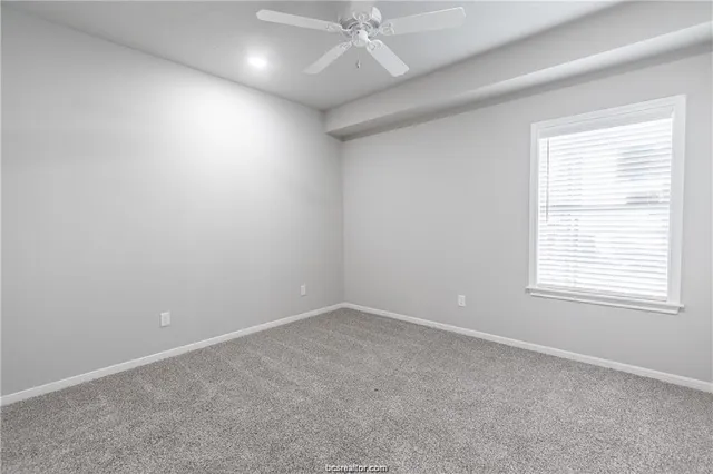 an empty room with a ceiling fan and window