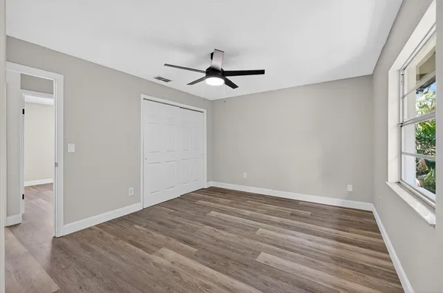 a view of empty room with wooden floor and fan