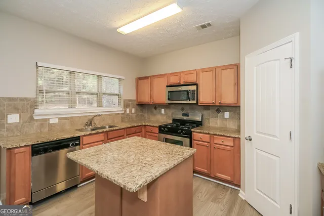a kitchen with stainless steel appliances granite countertop a sink stove microwave and refrigerator