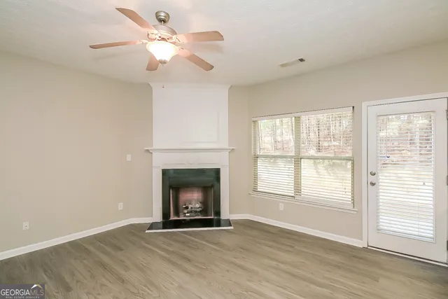 an empty room with windows fireplace and a fan