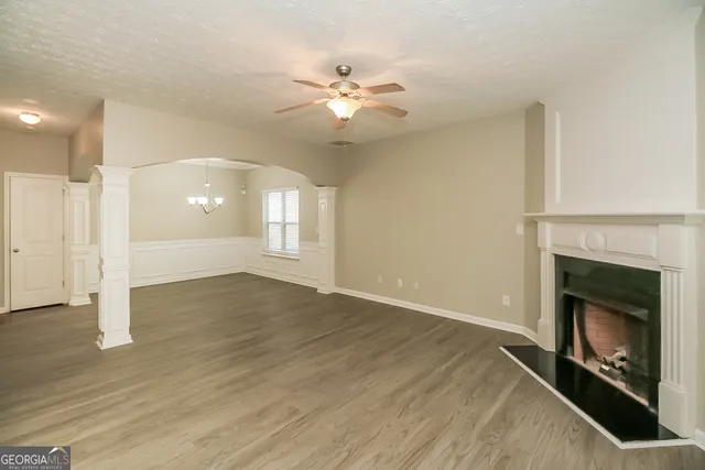 a view of an empty room with wooden floor fireplace and a window