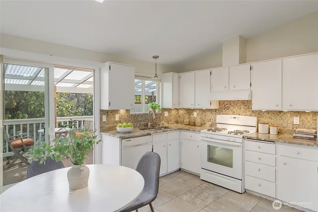 a kitchen with sink a stove and white cabinets