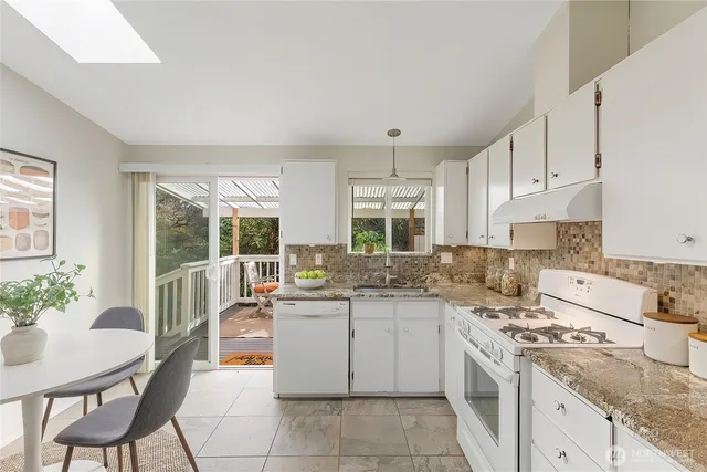 a kitchen that has a lot of white cabinets and stainless steel appliances