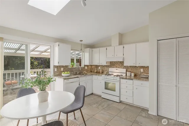 a kitchen with a stove a sink and white cabinets