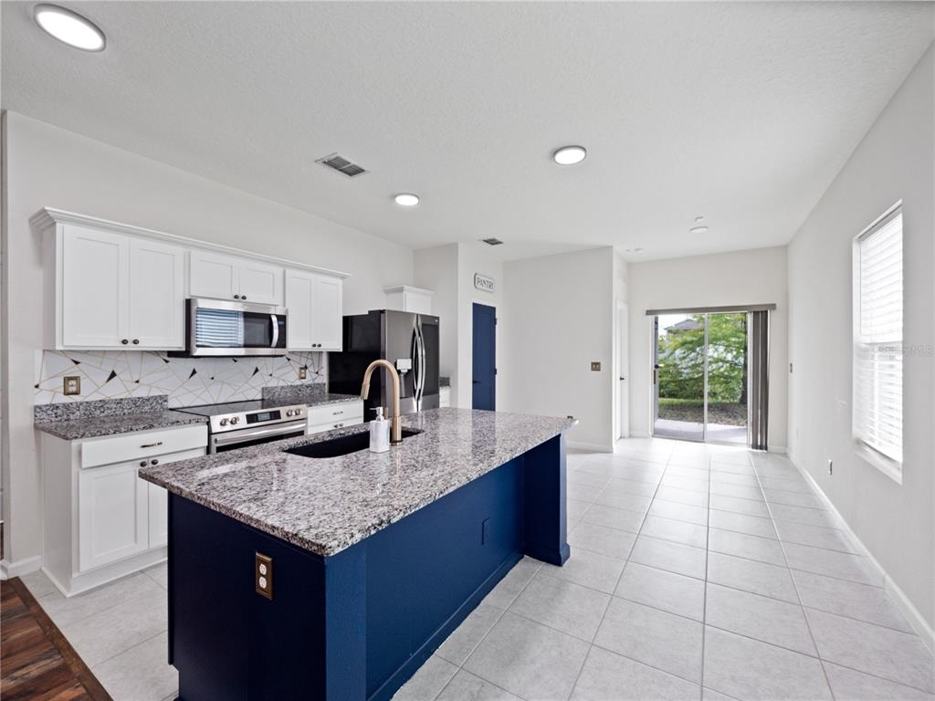 2249 Litchfield Loop DeLand, FL 32720 - Photo 11 of 27 a kitchen with granite countertop kitchen island a sink appliances and cabinets