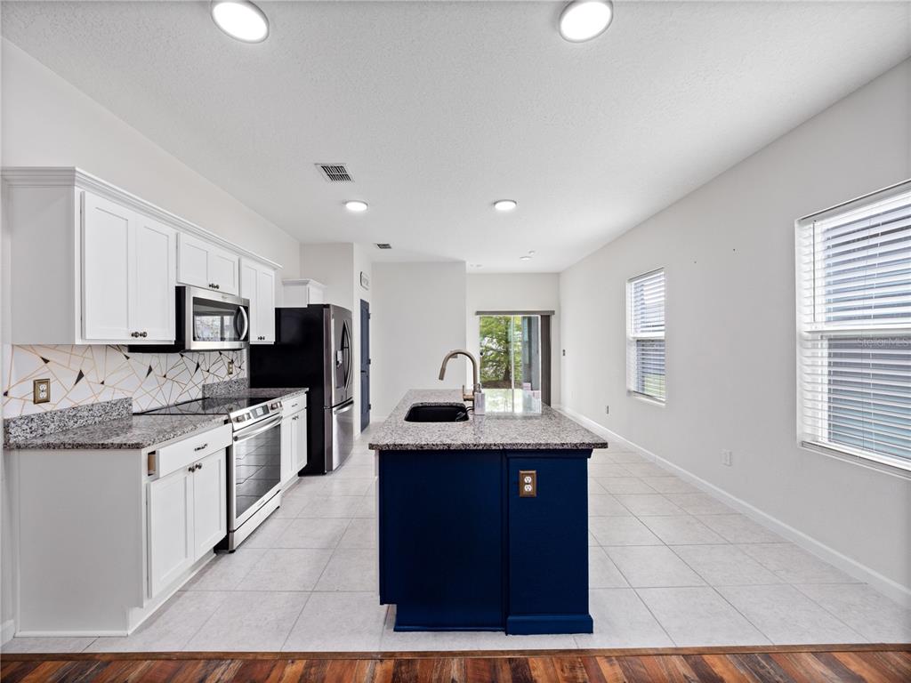 2249 Litchfield Loop DeLand, FL 32720 - Photo 9 of 27 a kitchen with stainless steel appliances granite countertop a sink stove and refrigerator