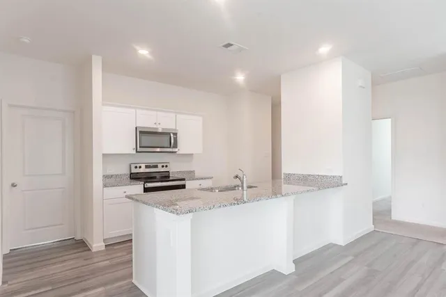 a kitchen with stainless steel appliances granite countertop a stove a sink and a refrigerator