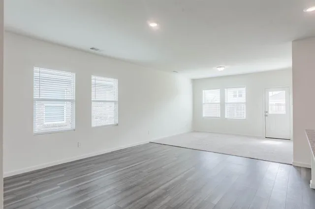 an empty room with wooden floor and windows
