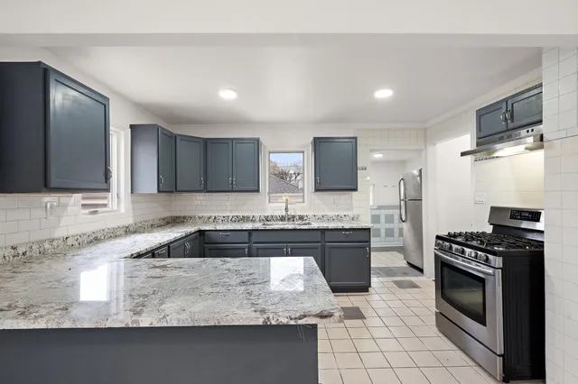 a kitchen with granite countertop a sink stainless steel appliances and white cabinets