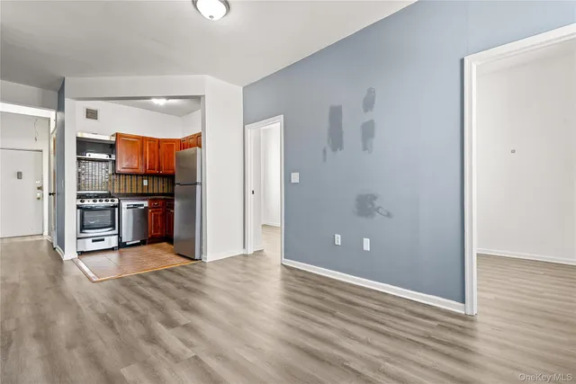 a view of kitchen and empty room with wooden floor