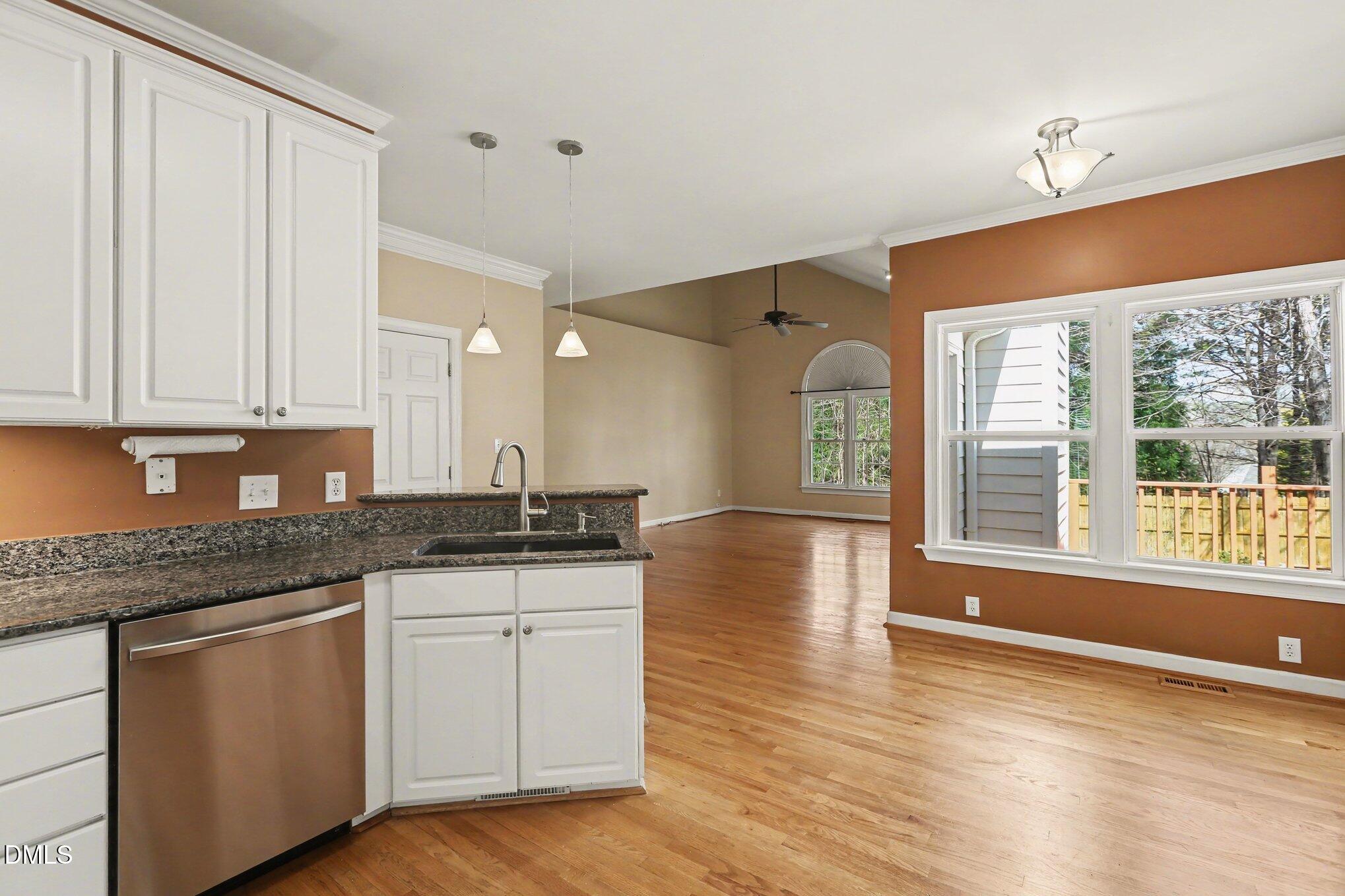 2616 Jasper Lane Raleigh, NC 27613 - Photo 15 of 44 a kitchen with granite countertop a stove a sink and white cabinets with wooden floor next to windows