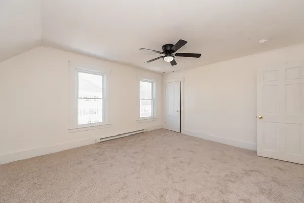 an empty room with a ceiling fan and windows