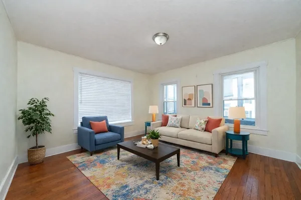 a living room with furniture a window and a wooden floor