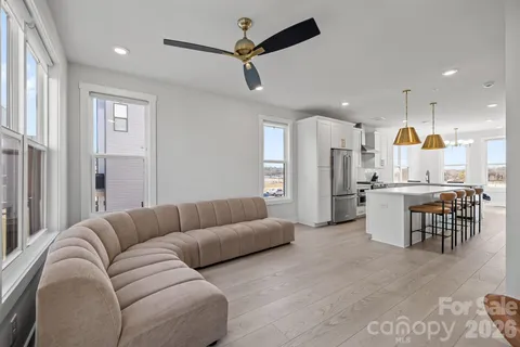 a living room with couches and kitchen view with wooden floor