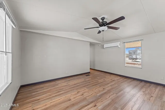 a view of an empty room with a window and wooden floor