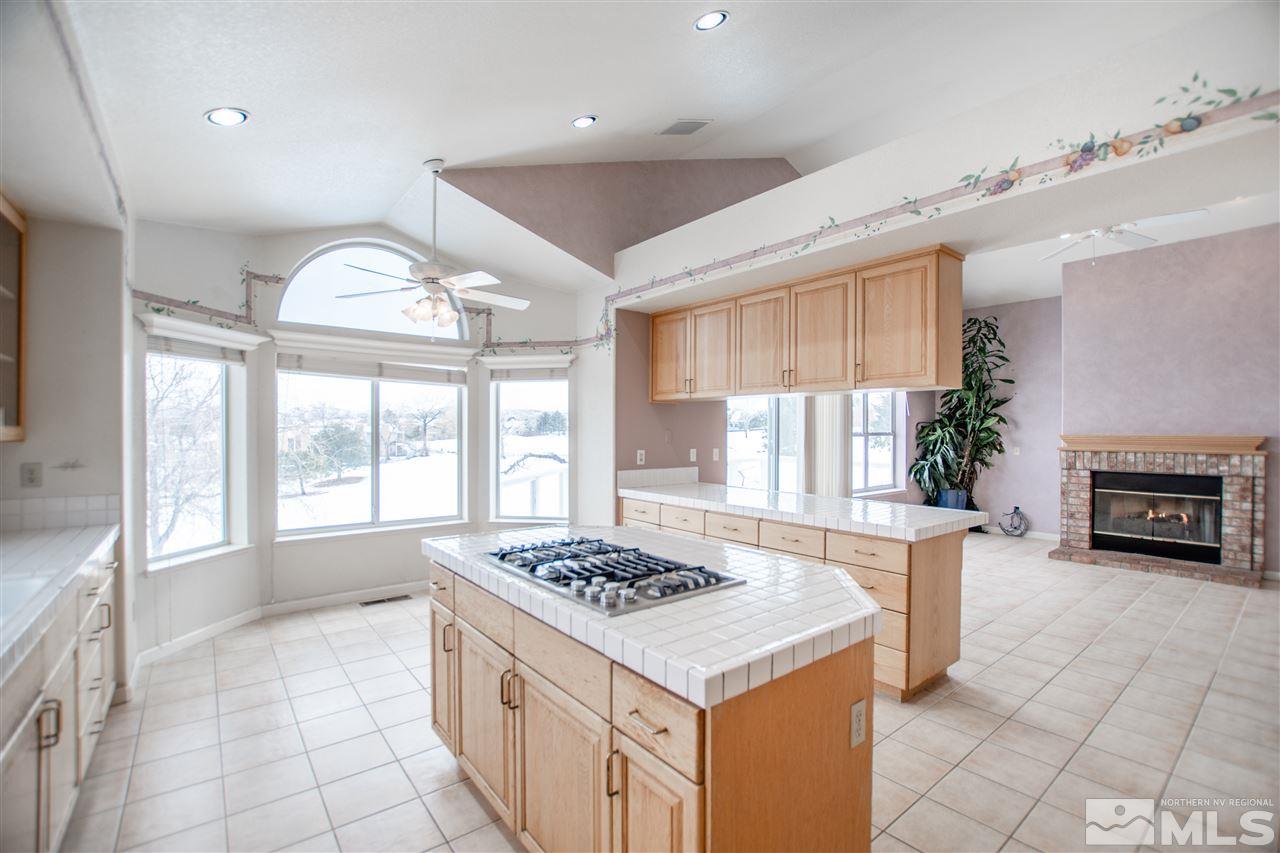 6174 Carriage House Way Reno, NV 89519 - Photo 10 of 22 a kitchen with a stove a sink dishwasher and a fireplace with wooden floor