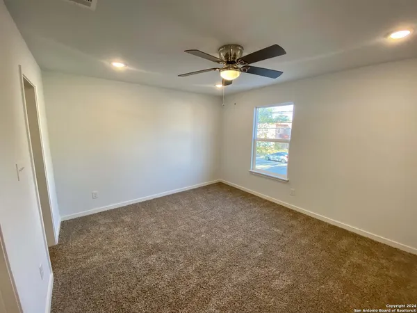 an empty room with closet and a chandelier fan