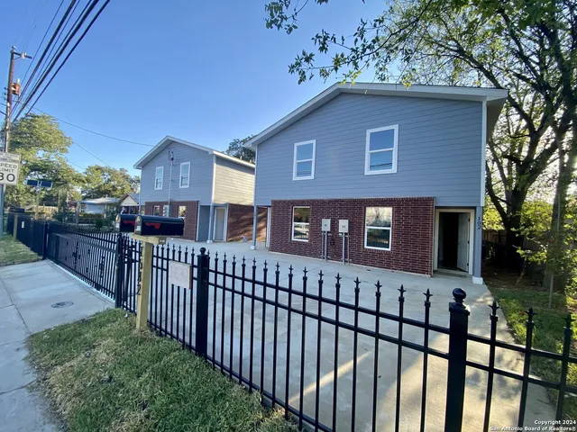 a view of a brick house with wooden fence