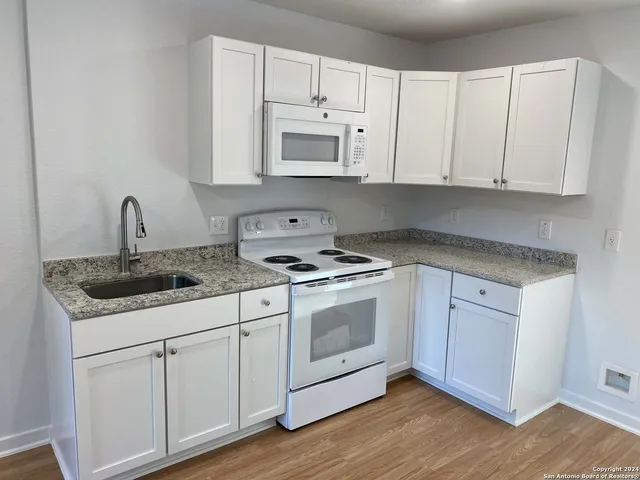 a kitchen with granite countertop white cabinets and white appliances