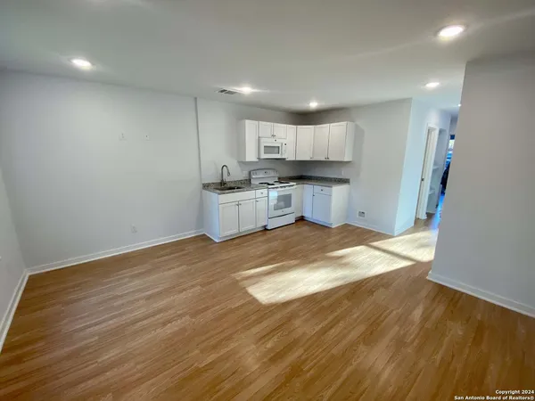 an empty room with wooden floor fan and windows