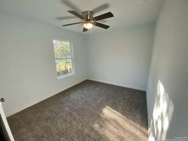 a view of an empty room and chandelier fan